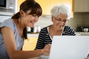 Sénior devant un ordinateur portable près d'une femme souriante