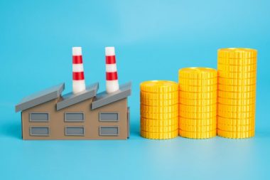 Industrial plant and growing stack of coins. Enterprise income. Payment of taxes. Industrial profitability and contribution to national budgets. Economic development. Tax from successful enterprises.