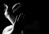 Black and white portrait of a woman hiding her face with hands. Stop violence against woman or mental health concept. Studio shot.