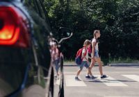 Children next to a car walking through pedestrian crossing to th