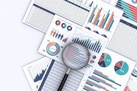 ビジネスデータをプリントした書類と虫メガネ