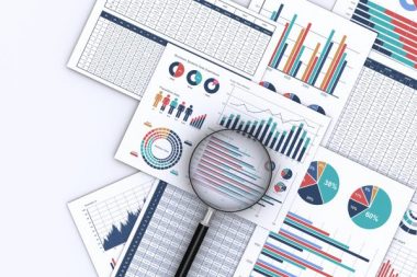 ビジネスデータをプリントした書類と虫メガネ