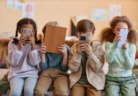 Group of young children holding smartphones and hiding faces