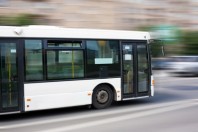 white city bus goes along street