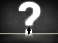 Business man looking at wall with a bright question mark